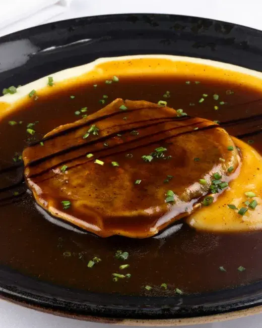 Plato de carne bañado en abundante salsa marrón y cebollino.