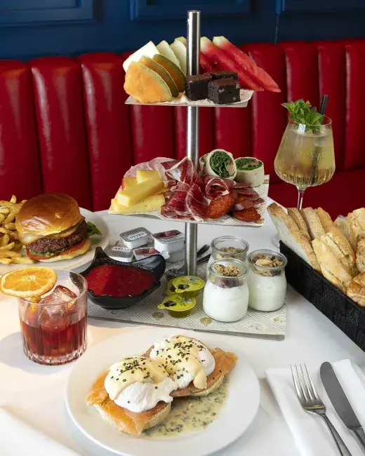 Completa torre de brunch con embutidos, huevos benedictinos y cócteles.